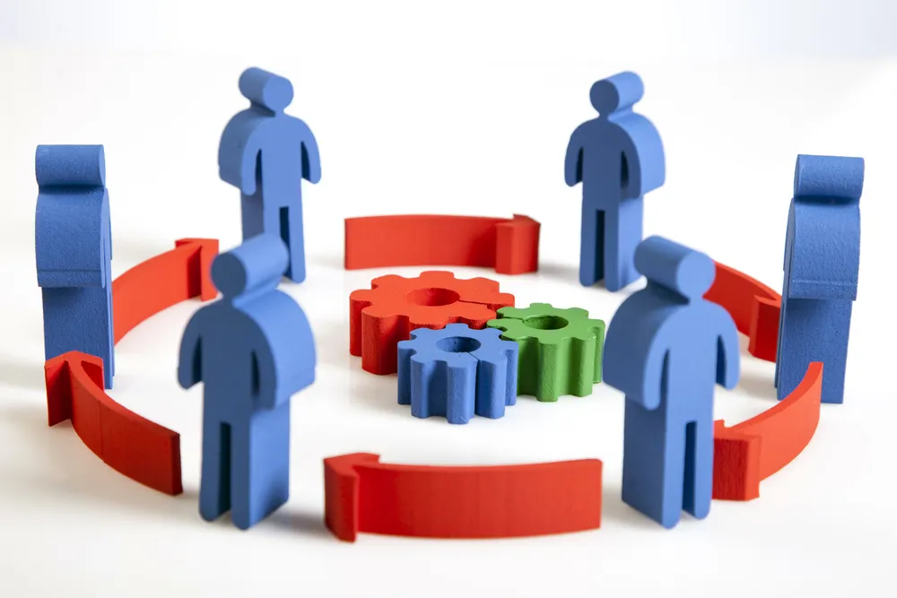 Figuras azules en círculo con flechas rojas y engranajes centrales representando la metodología pdca en equipo.