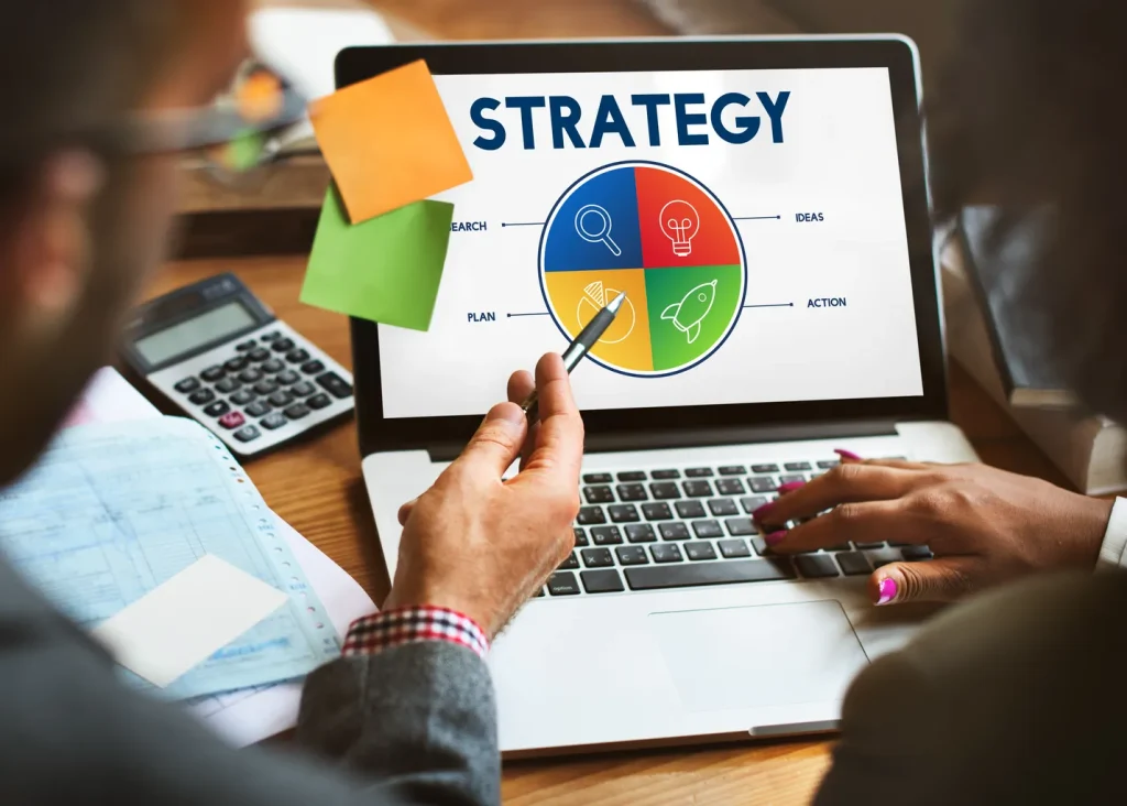 Vista de la parte posterior de unos empresarios en donde se puede ver una computadora con una estrategia basada en una de las etapas de la planeación estratégica.